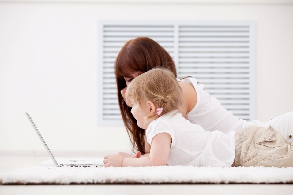 Mother and baby on carpet with laptop